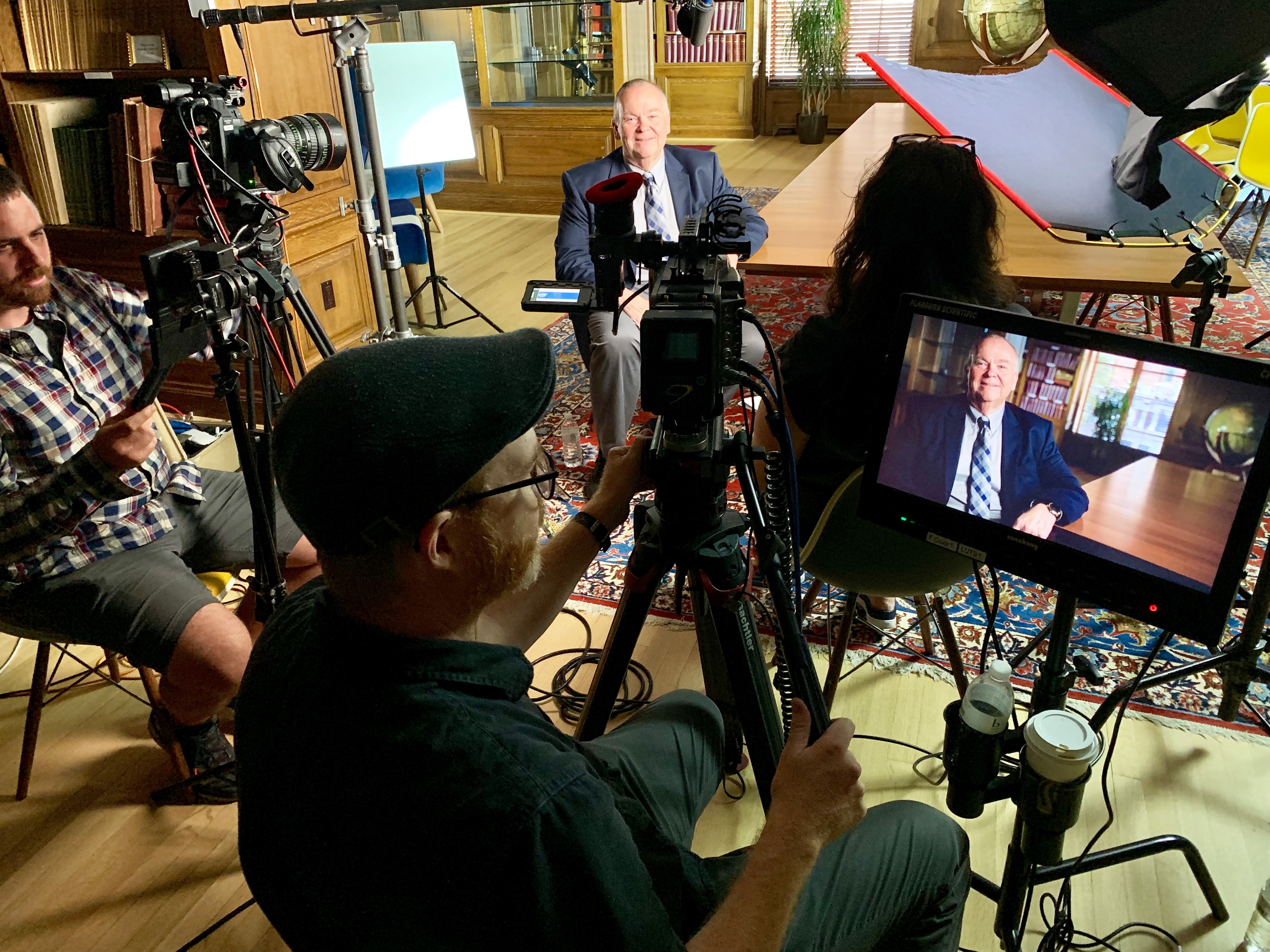 Mark Fallon being filmed by a full documentary crew in a wood-panelled library setting