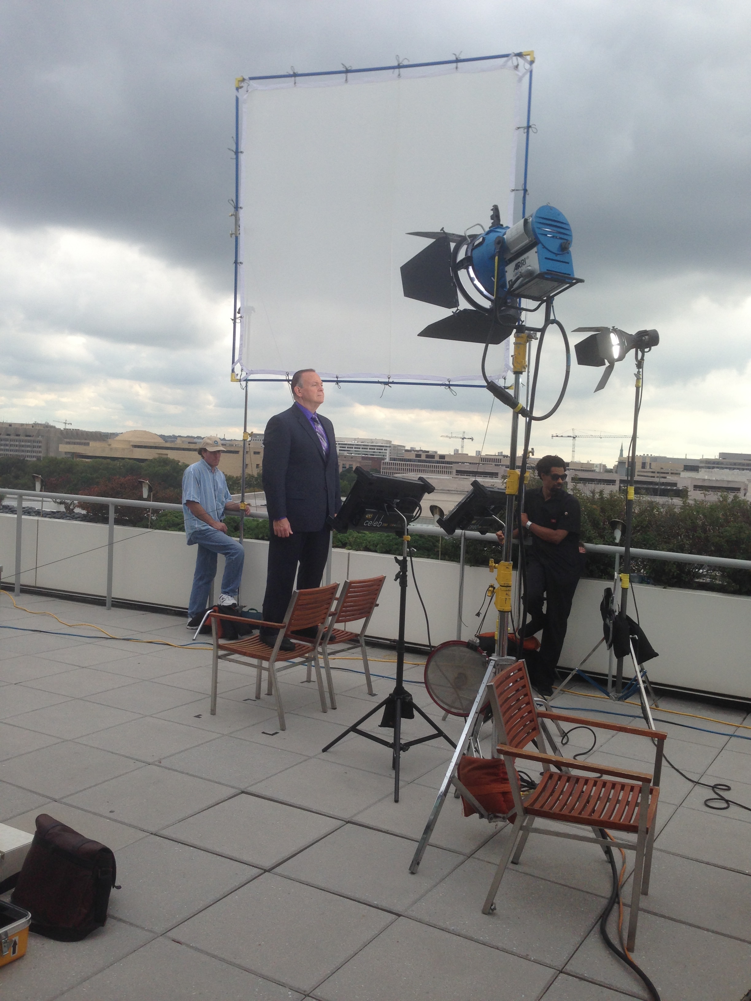 Mark Fallon on a rooftop location shoot with film crew and lighting equipment